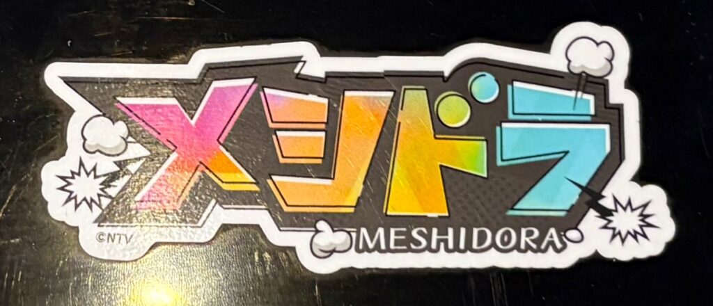 お店のレジに貼ってあった「メシドラ」シール